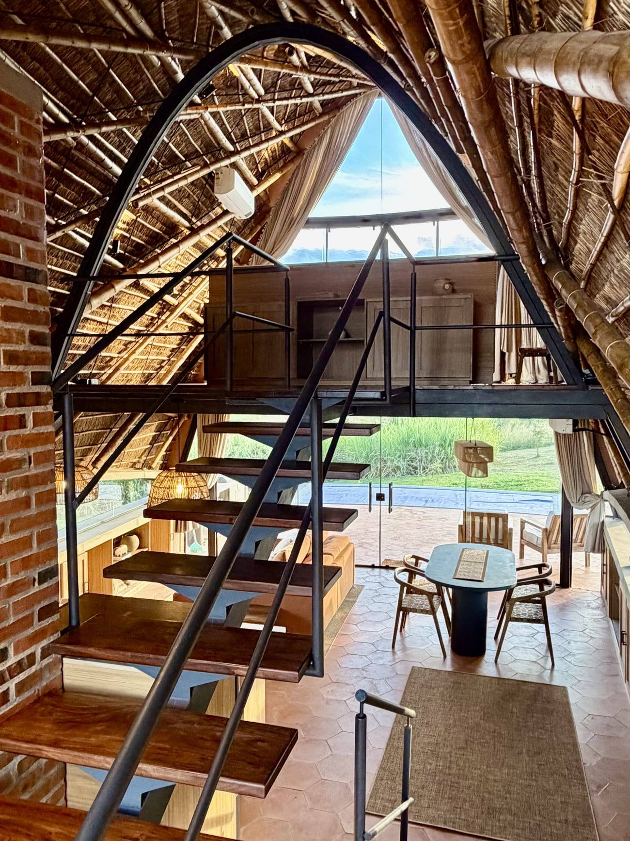 El interior a doble altura: escalera de madera, bóveda de tacuara y pared de ladrillo.
