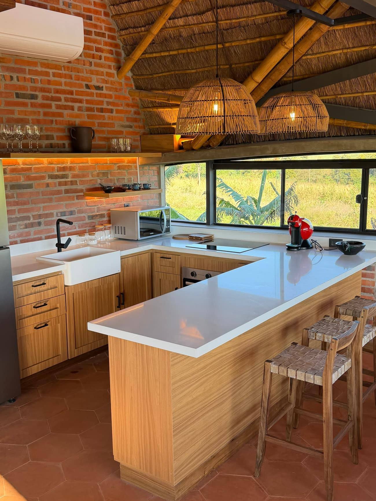 La cocina: mesada clara, alacenas de madera y la ventana al verde detrás.