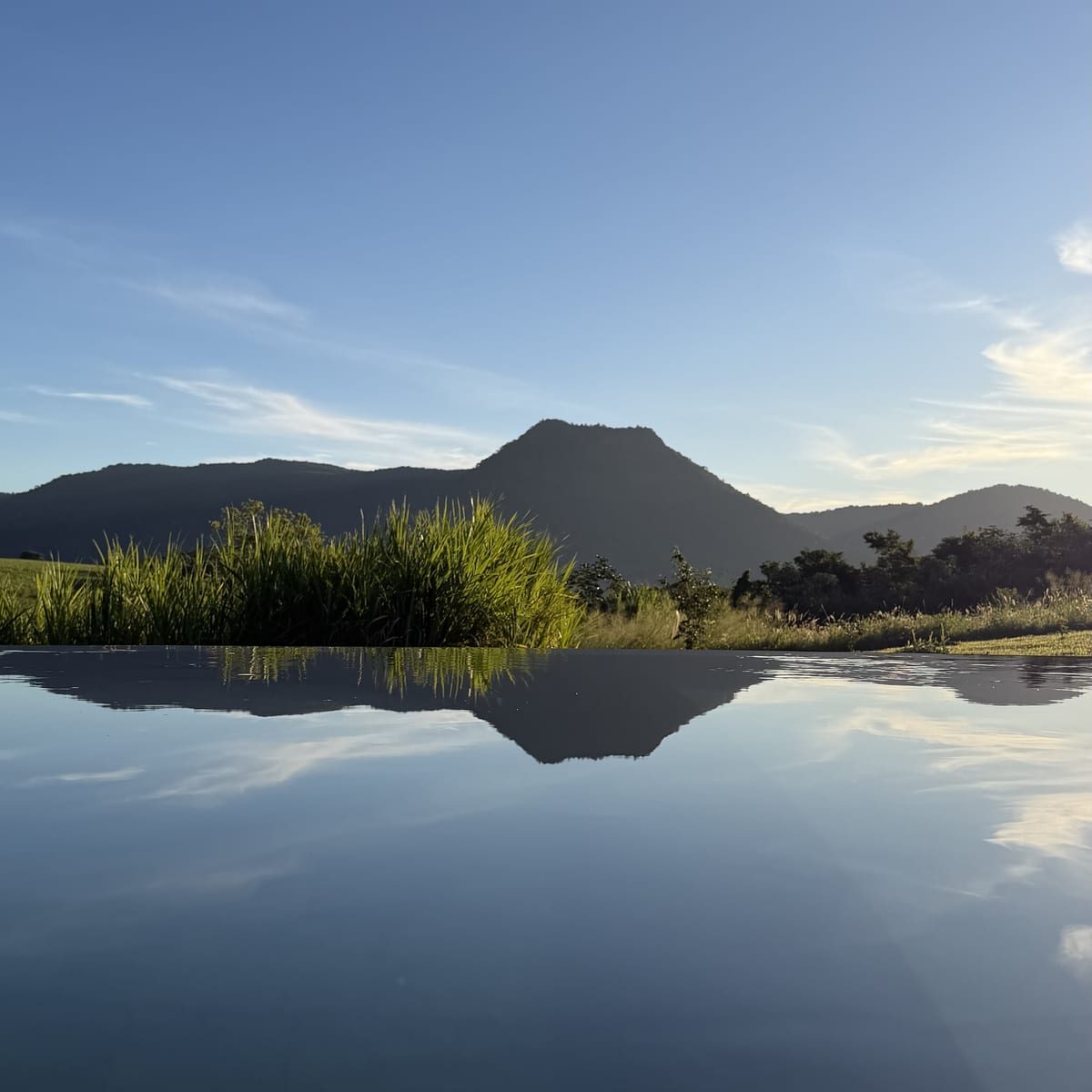 La piscina quieta al atardecer, devolviendo el cerro como un espejo.