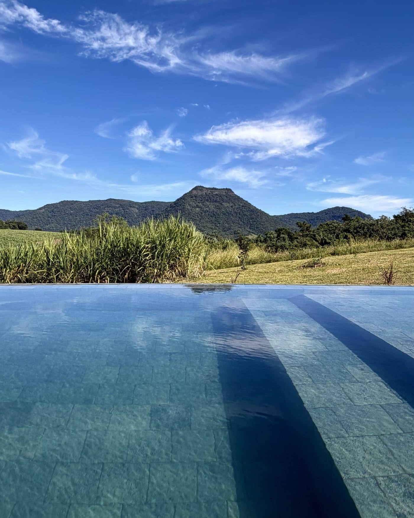 La piscina al mediodía, con el agua clara y el Cerro Amor recortado contra el cielo azul.